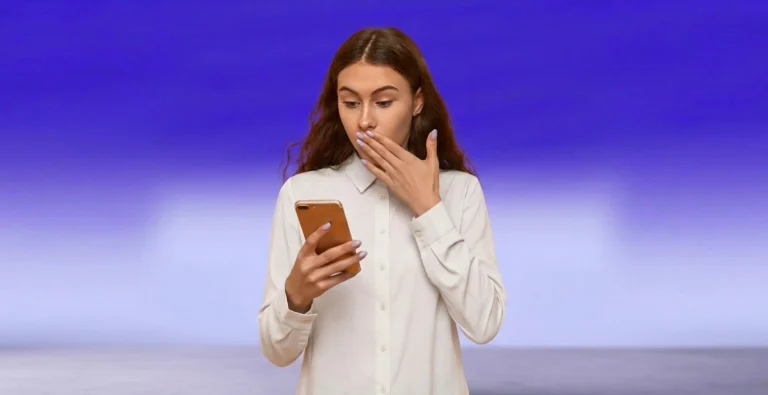Una mujer mira su móvil, sorprendida por el mensaje fraudulento que acaba de recibir.